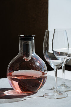 Carafe with pink drink and empty glasses on table