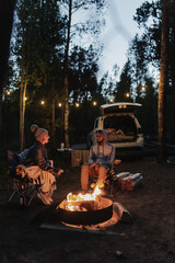 Camp fire in the forest. Sitting by the fire. Relax and leisure. National park forest. Two people campers are on vacation. Road trip vacation. Local traveling. Camping season. Fourth of July.