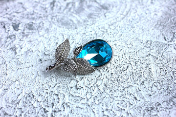 Vintage flower brooch with a blue crystal topaz gem on a pin clasp for decorating a scarf, jacket...
