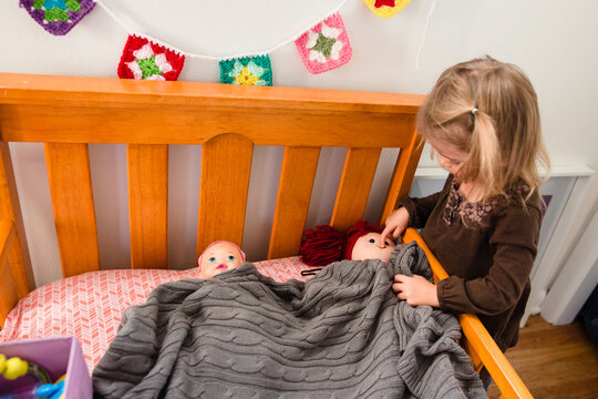 little girl tucks in dolls
