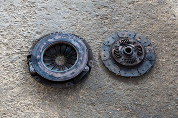 Old Disc Clutch and cover on floor. Old rusty clutch and the disc lies in the garage. Car rusty clutch pressure plate assembly  with clutch disc plate and fly wheel