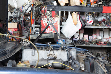 Engine hanging on crane hook on car repair service. Photo of old engine hanging on a cable. Engine hanging for overhaul.