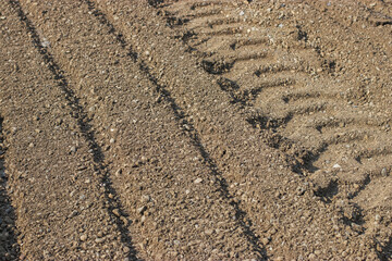 Traces of construction machinery wheels on sand and gravel. Road repair on a sunny summer day.