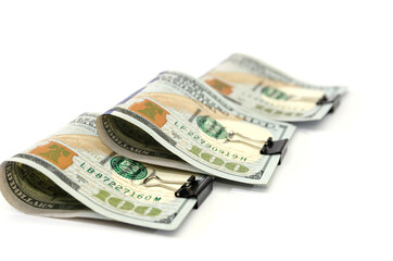 one hundred dollar bills fastened with clips on white.