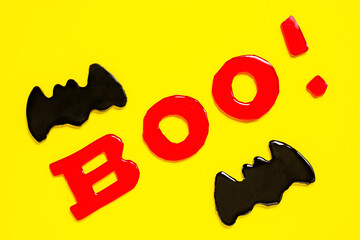 halloween flat lay, inscription boo, black bat on a yellow background, holiday background, postcard. Halloween decoration concept.