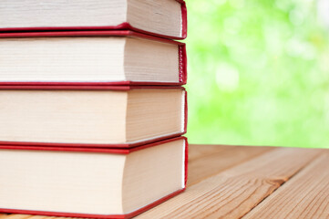 stack of books on the wood table in the green nature background