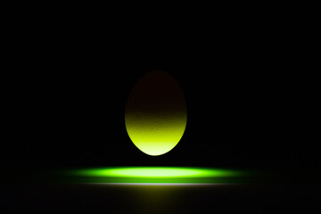 Green egg levitating over a black glass table