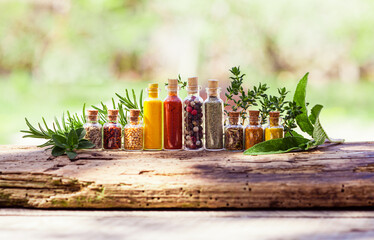 Row of bottles with spices and fresh herbs behind