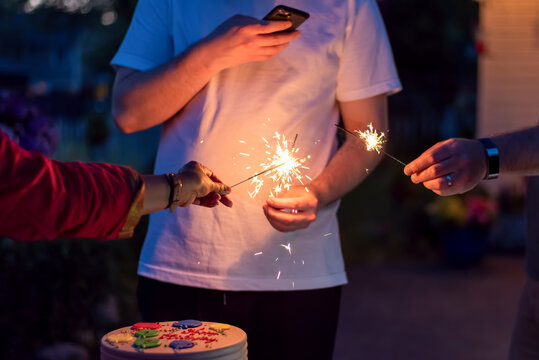 Snapping a picture of a sparkler and birthday cake at a family celebration