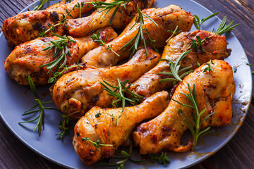 Grilled chicken drumsticks on dark plate, top view