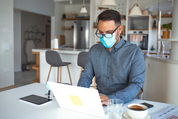 Male entrepreneur analyzing business reports while wearing face mask and working in the office during virus epidemic. Male employee wearing a health mask Preventing corona virus infection covid-19