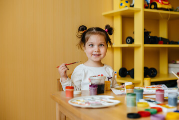 A cute little girl is playing and painting in her room. Recreation and entertainment