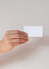 Hand holding empty white business card.