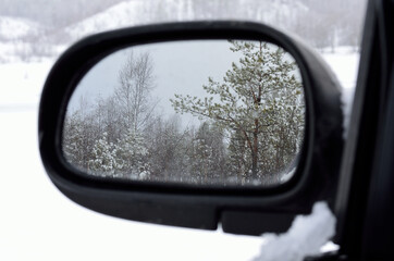 Snowy and magic arctic landscape in car mirror