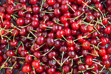 Juicy red berries of a cherry are washed in water. Ripe fruits ripped from petioles. Making jam, canning products at home. Food, kitchen. Close-up. Background. View from above