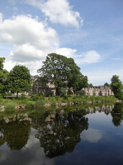 A general view alongside River Kent with old stone houses and trees in Kendal, Cumbria, England, UK.