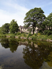 A general view alongside River Kent with old stone houses and trees in Kendal, Cumbria, England, UK.
