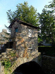 Obraz premium The Bridge House, a 17th century stone house over Stock Beck in Ambleside town, Lake District, Cumbria, England, UK.