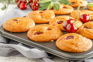Homemade cherry muffins and fresh cherries on a light background. Delicious dessert