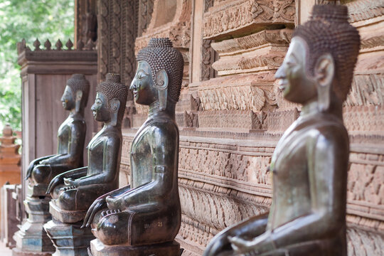 Vientiane, Laos. Sitting shinny bronze  Buddhas guarding a temple entrance. 
