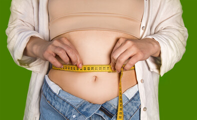 girl measures the volume of the waist with a measuring tape on a green background