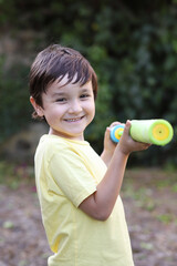 niño con un churro de lanzar agua apuntando a cámara