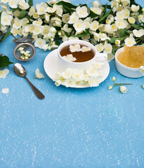 Healthy Herbal Flower tea. Tea cup with Jasmine Flowers and Crystal Sugar on blue grunge textured background. Herbal Medicine. White Spring Flowers. Copy space

