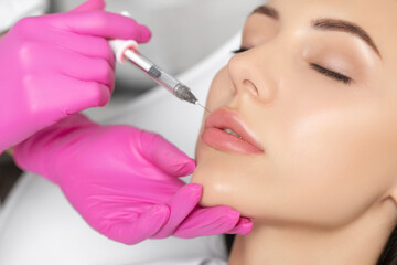 Woman with beautiful clean skin. Cosmetologist does injections for lips augmentation and anti...