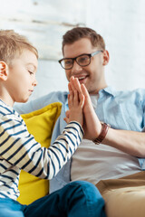 selective focus of smiling man giving high five to adorable son