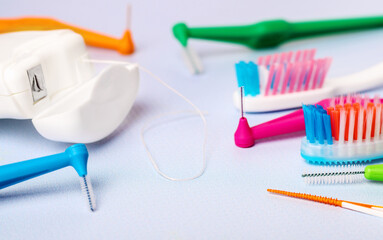 Different interdental toothbrushes, dental floss and toothbrushes on blue background, small depth of focus. Dental and orthodontic concept.