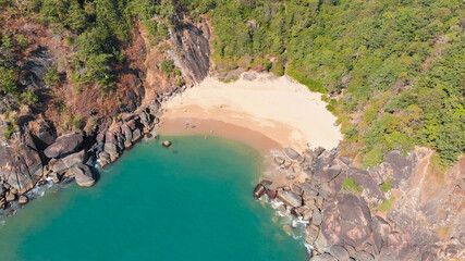 Beautiful secret beach Butterfly in Goa, India. Aerial view of pristine beach with rocky bay and waves crashing.