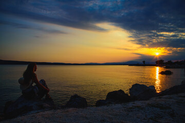 Silhouetted by a girl who looks at the sunset.