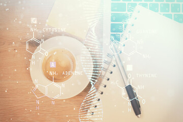 DNA hologram drawings over computer on the desktop background. Top view. Multi exposure. Concept...