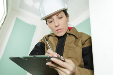 female contractor on indoor site making notes on clipboard
