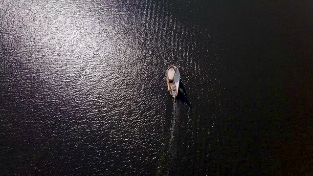 Top down aerial of old botter boat sailing over sea in summer