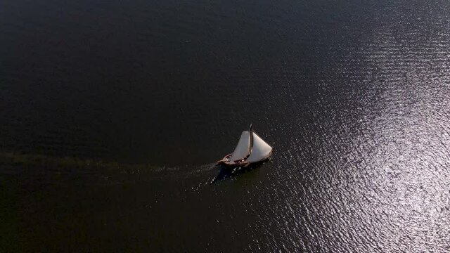 Static aerial of sail boat sailing on open sea in summer