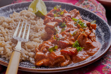 traditional chicken korma and rice, with herbs and lime wedge.