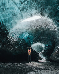 Traveler in ice cave in Iceland. Climber with an ice axe on the Vatnajokull glacier. Epic landscape of travel and adventure content.