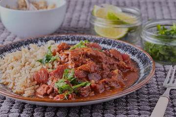 Chicken curry and rice, with some lime wedges in the background.