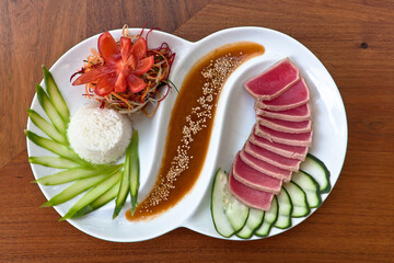 plato de sashimi de atún rojo crudo en rebanadas con vegetales y salsa a la mostaza, plato blanco...