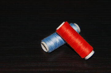 Rolls of colored cotton threads for hand and machine stitching.Isolated on black background and arranged unevenly.