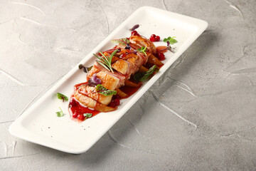 sliced duck breast with lingonberry sauce and microgreen closeup on white plate and concrete background