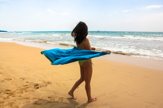 Beautiful girl with dark long hair is dancing on the ocean coast, summer holidays.