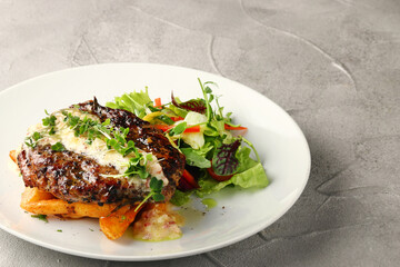 grilled beef with potato and salad closeup on white plate and concrete background