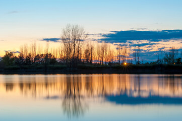 beautiful colors at sunset, with trees reflected in the lake.Long exposure