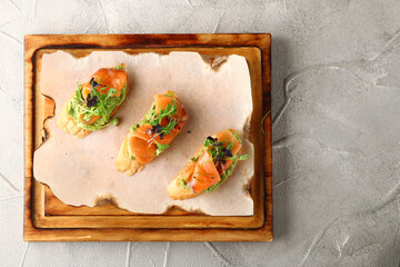 salmon toast with guacamole on wooden deck top view. Healthy breakfast or lunch. Delicious homemade smoked salmon gluten free canape