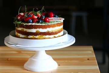 biscuit cake with berries on wooden table and dark background. cake with sweet cherry and blueberry