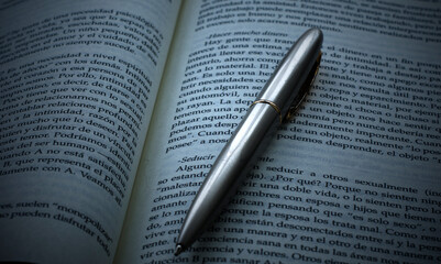 A Book with a silver pen. Close up view.