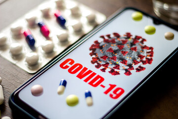 In this photo illustration pharmaceutical pills are seen displayed on a table with a COVID-19 inscription on the mobile screen. Dexamethasone, Hydroxychloroquine are used to treat coronavirus disease.