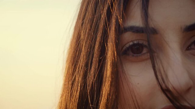 Cinematic shot of half face of beautiful young woman looking playful and dark hair covered eye in close up. Happy and successful lifestyle concept